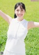 A woman in a white shirt and pleated skirt posing for a picture.